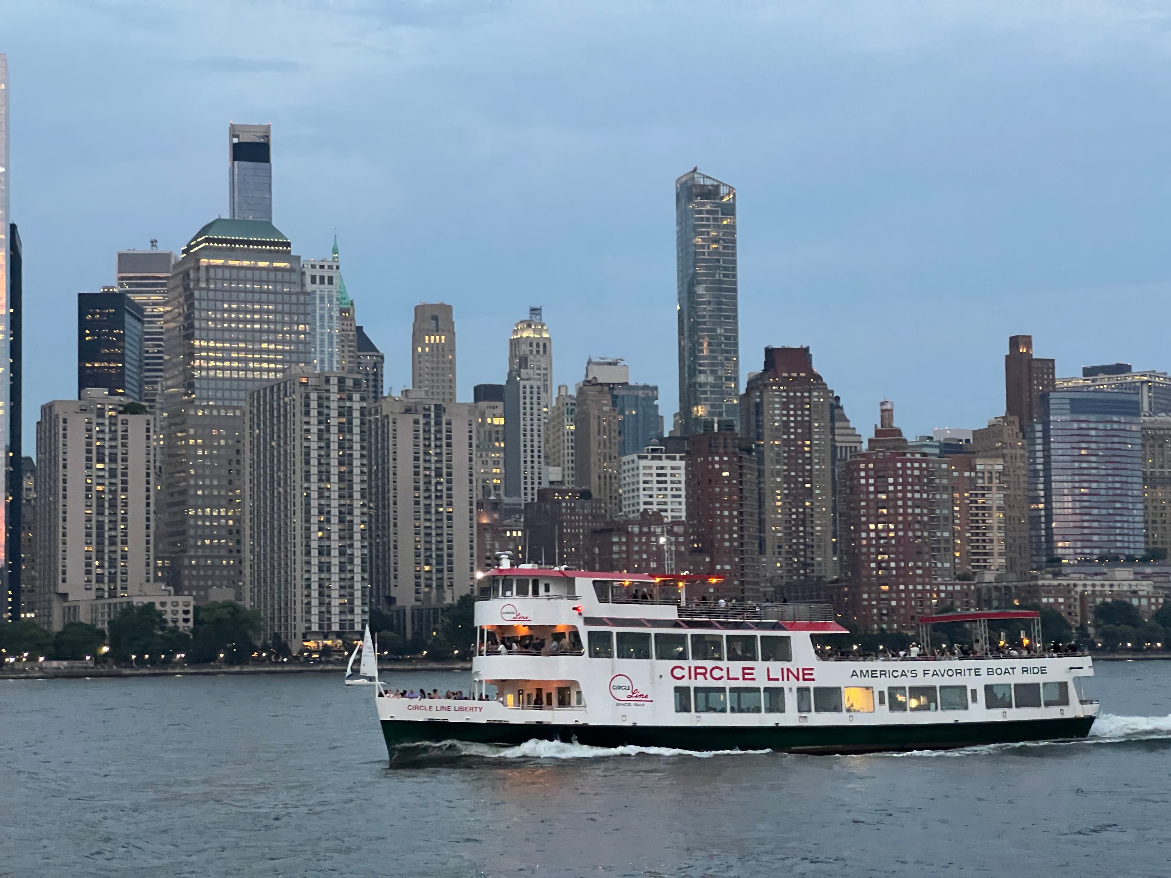 Sightseeing vessel on the water with the New York City skyline — iconic urban waterfront experiences and city tour operators